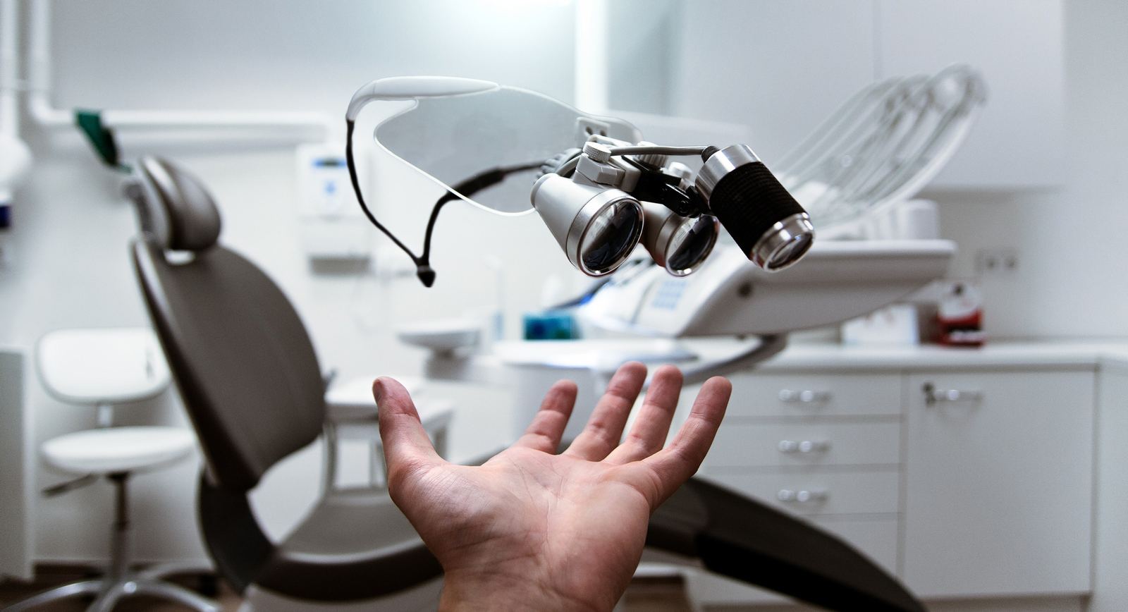Una poltrona odontoiatrica con lo specchietto e le lenti d'ingrandimento sospese sopra una mano